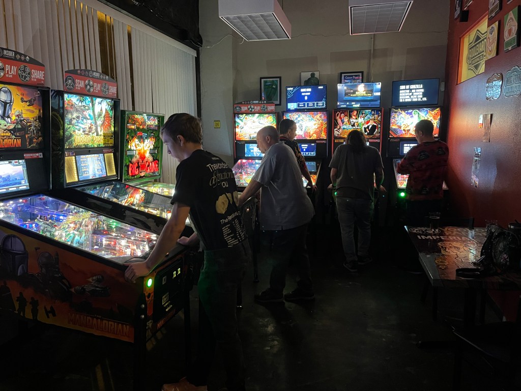 A group of people playing pinball at 417 Taphouse